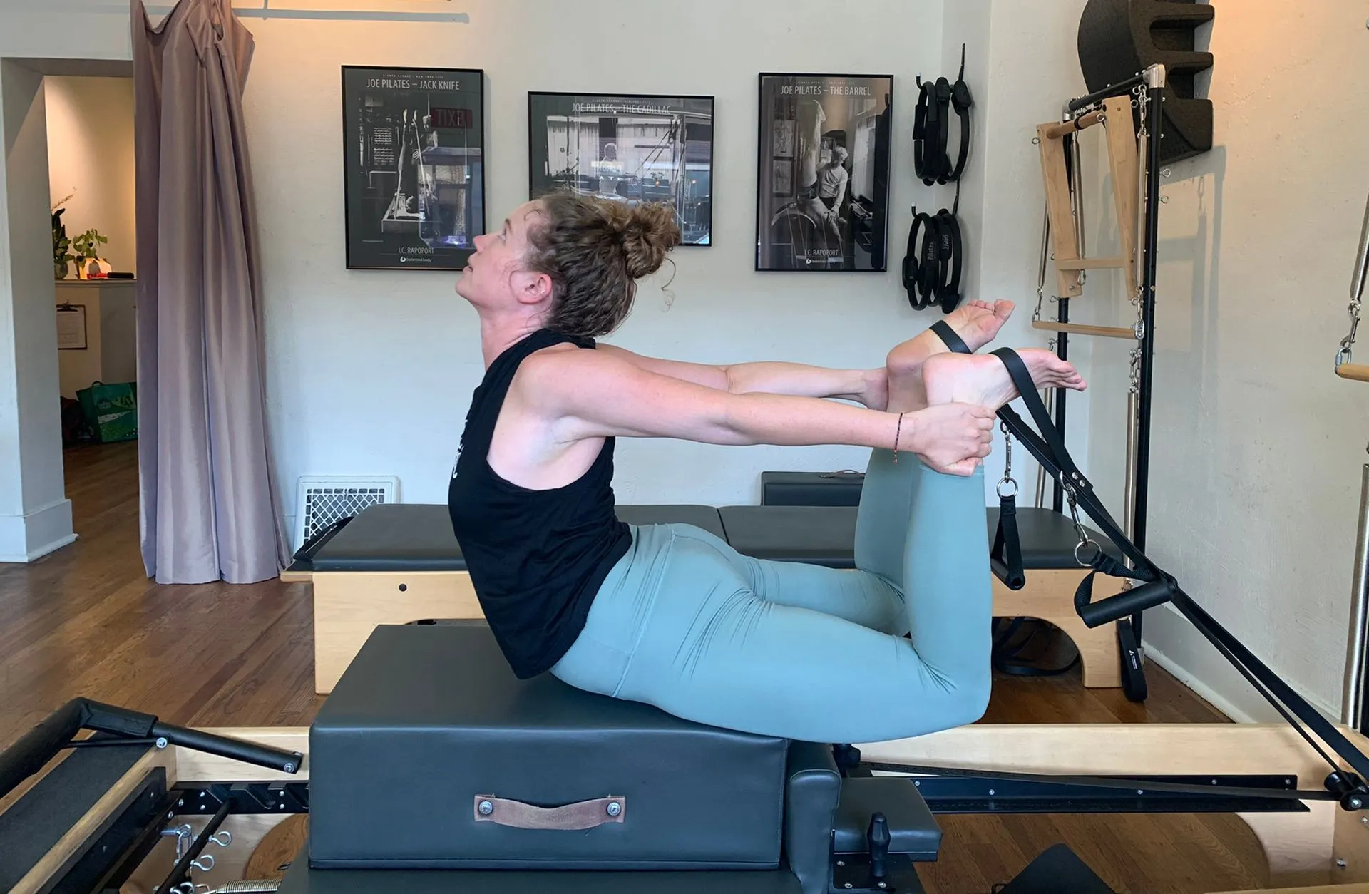 A client arcs backward over a reformer mid-exercise at Denver Pilates Movement's LoHi studio